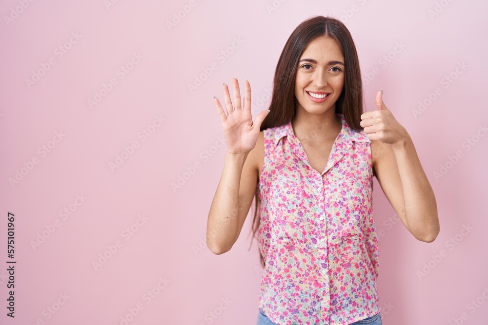 Young hispanic woman with long hair standing over pink background showing and pointing up with fingers number six while smiling confident and happy. Young hispanic woman with long hair standing over pink background showing and pointing up with fingers number six while smiling confident and happy.