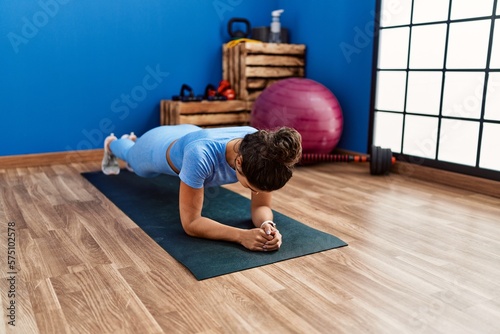 Young latin woman training abs exercise at sport center