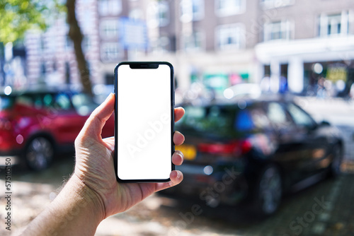 Man holding smartphone showing white blank screen at car parking