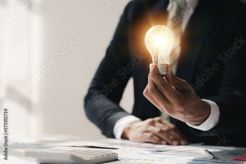 Standing man hold glowing light bulb, Creative new idea. Innovation, brainstorming, strategizing to make the business grow and be profitable. Concept execution, strategy planning and profit management photo