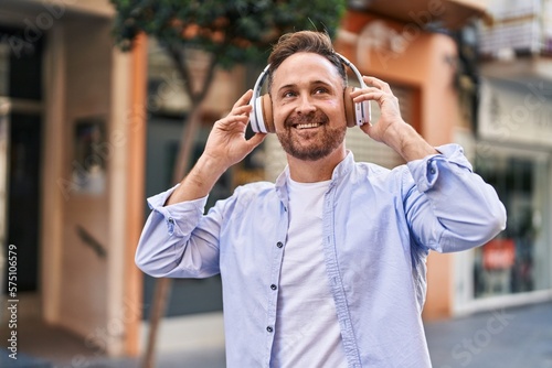 Young caucasian man smiling confident listening to music at street