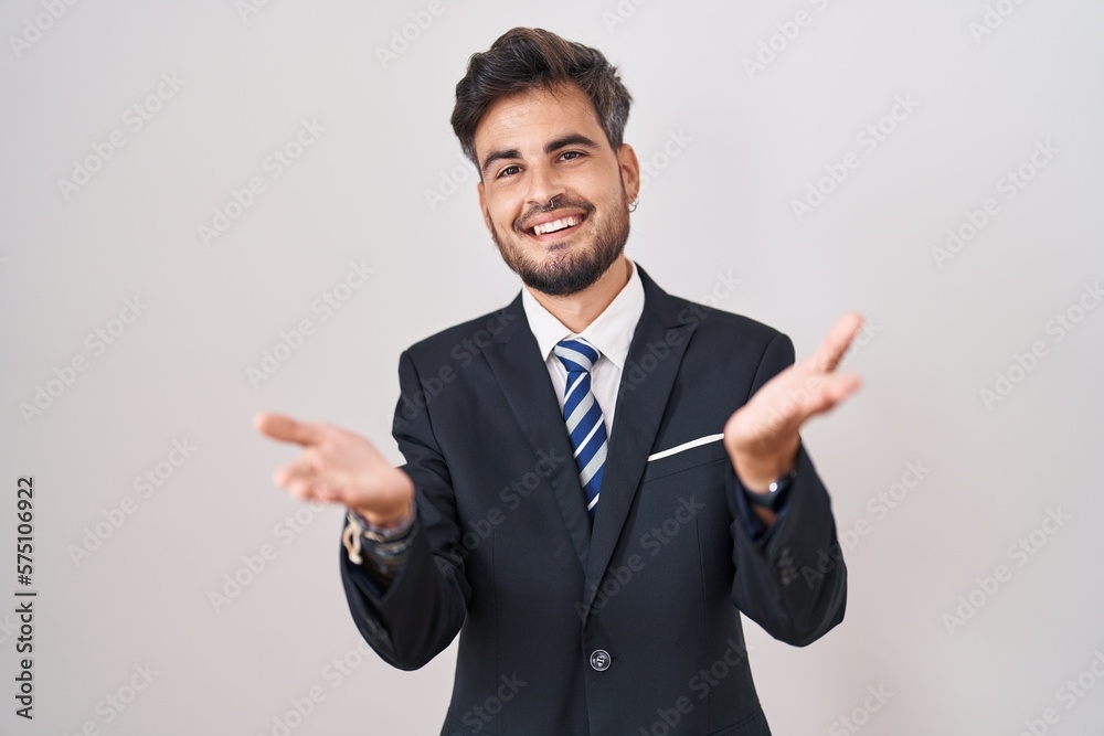 Young hispanic man with tattoos wearing business suit and tie smiling cheerful offering hands giving assistance and acceptance. Young hispanic man with tattoos wearing business suit and tie smiling cheerful offering hands giving assistance and acceptance.