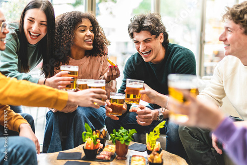 Multiracial friends drinking and toasting beer at brewery bar pub-Happy diverse people cheering glasses and having fun enjoying happy hour celebrating party-Beverage life style concept with guys 