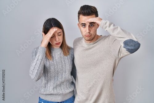 Young hispanic couple standing over white background worried and stressed about a problem with hand on forehead, nervous and anxious for crisis