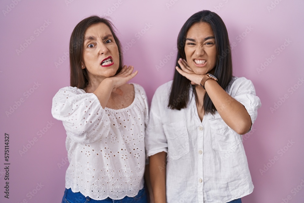 Hispanic mother and daughter together cutting throat with hand as knife, threaten aggression with furious violence Hispanic mother and daughter together cutting throat with hand as knife, threaten aggression with furious violence