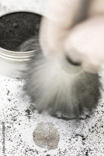 Ein Kriminaltechniker sichert eine daktyloskopische Spur mit einem Pinsel und Rußpulver