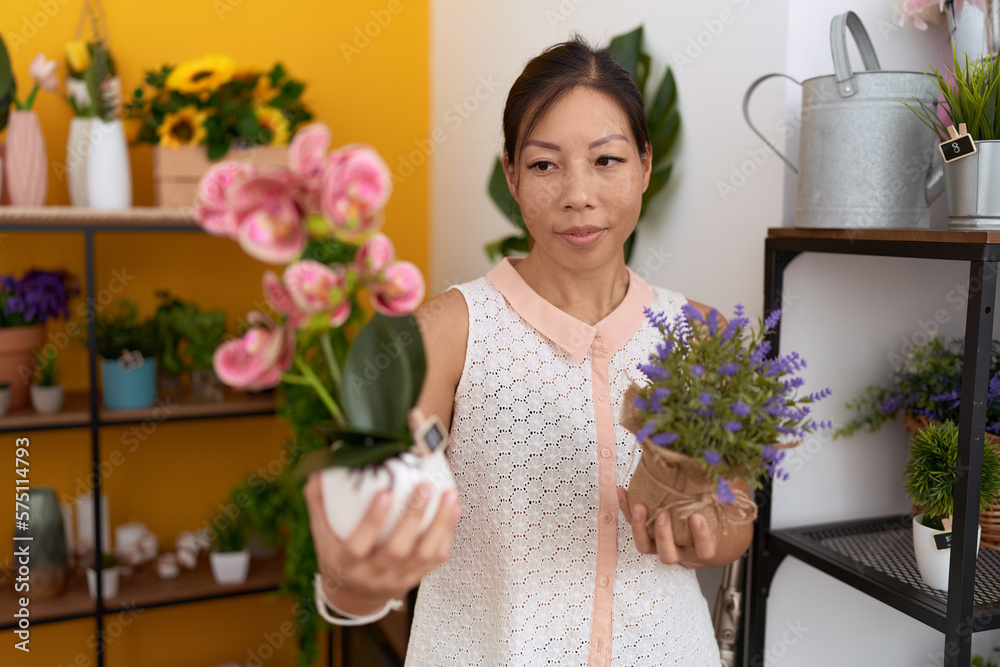 Young asian woman florist holding plants at flower shop Young asian woman florist holding plants at flower shop