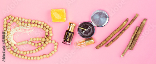 happy ramadan concept, rosary, siwak and perfume and compass on pink background