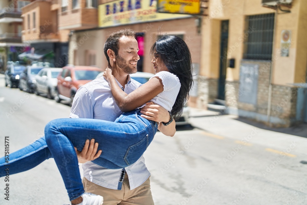 Man and woman interracial couple holding in arms at street