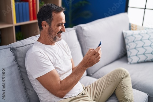 Middle age man using smartphone sitting on sofa at home © Krakenimages.com