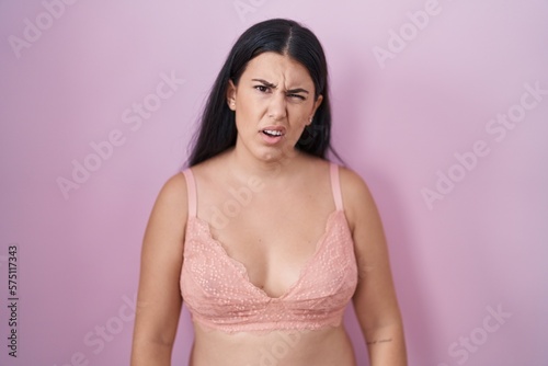 Young hispanic woman wearing pink bra looking sleepy and tired, exhausted for fatigue and hangover, lazy eyes in the morning.