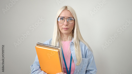 Young blonde woman preschool teacher holding books with relaxed expression over isolated white background