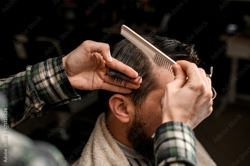 Φωτογραφία close-up the hand holds a strand of wet male hair and combs it with a comb