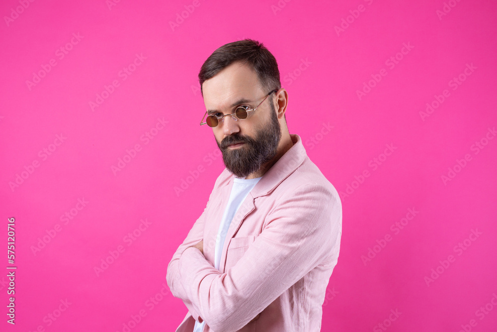 Bearded man dressed in a pink jacket with glasses. Emotional studio portrait. Bearded man dressed in a pink jacket with glasses. Emotional studio portrait.