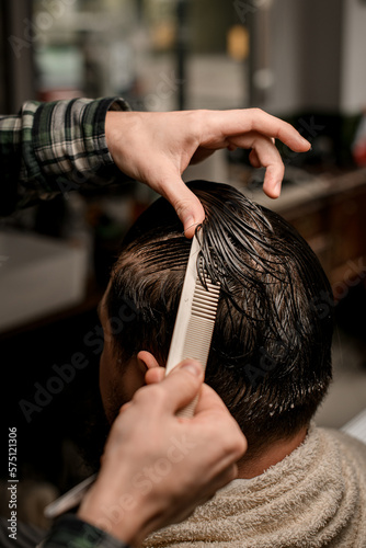 Fotobehang Close-up view of barber hands accurate combs wet male hair and make new style for client