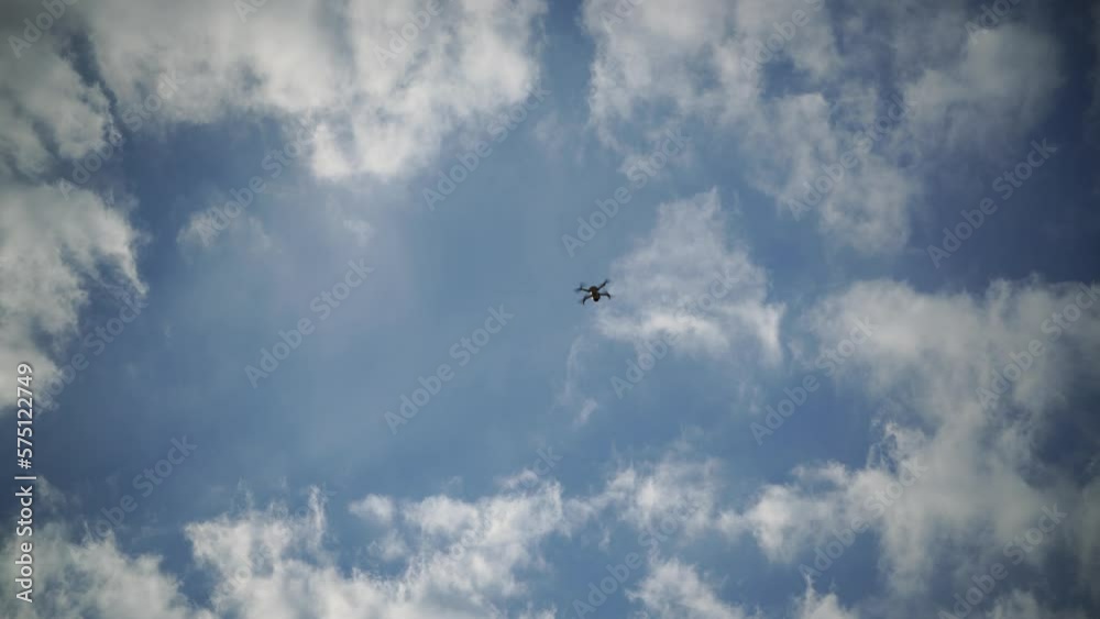 Hovering drone flying upward on a cloudy sky backdrop Hovering drone flying upward on a cloudy sky backdrop