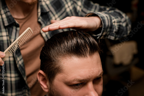 Fotobehang close-up on styled hair of man and hand of barber with comb