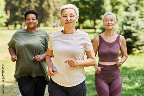 Waist up portrait of active senior women running towards camera outdoors and enjoying sports