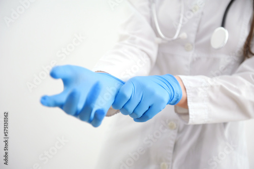 Close up Scientist hands putting in nitrile blue latex gloves in labcoat wearing nitrile gloves, doing experiments in lab. High quality photo