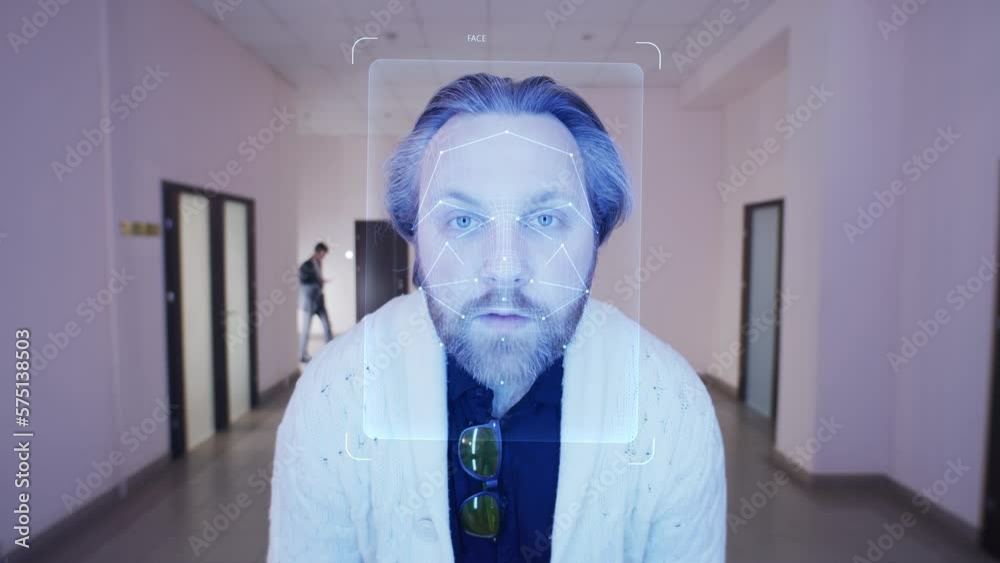 Adult man scans his face in coworking office. He touches sensor and security system identifies him showing personal virtual profile. 3D hologram of human biometric facial recognition. AI technology.