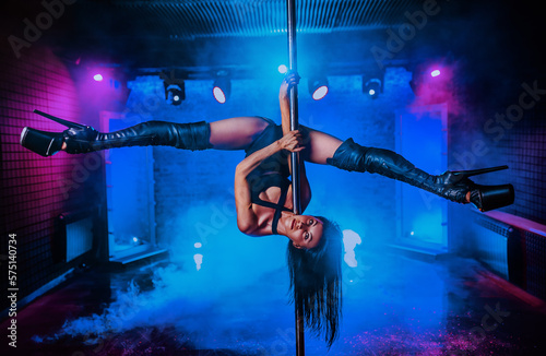 Young woman pole dancing in night club interior photo