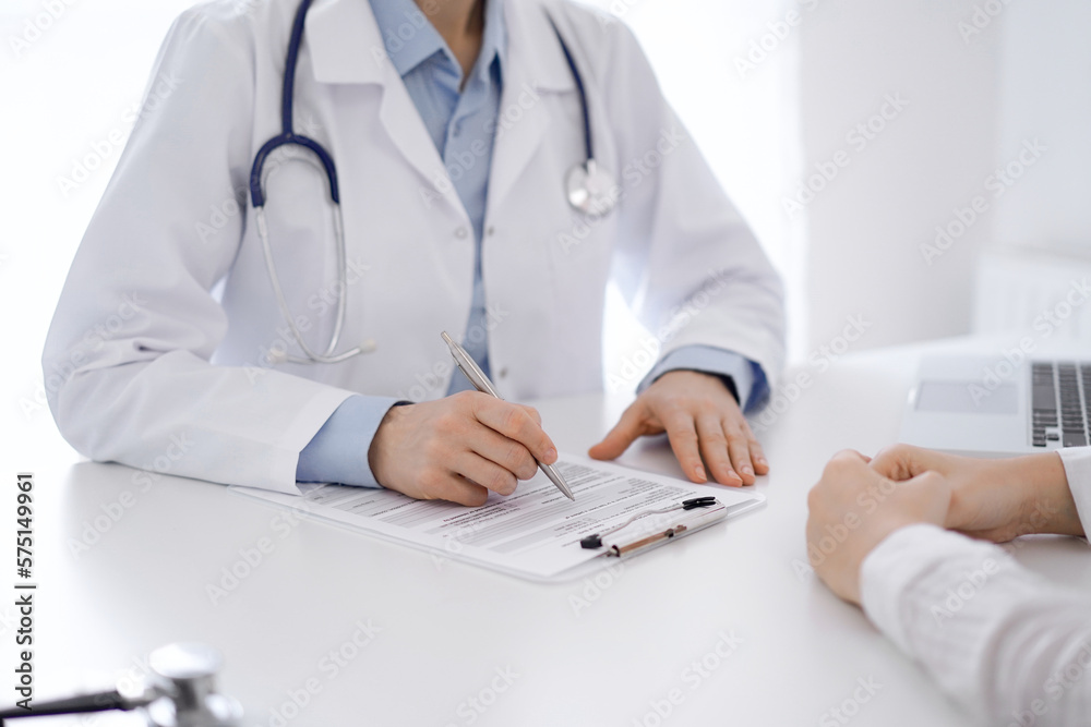 Doctor and patient discussing current health questions while sitting opposite of each other at the table in clinic, just hands closeup. Medicine concept Doctor and patient discussing current health questions while sitting opposite of each other at the table in clinic, just hands closeup. Medicine concept