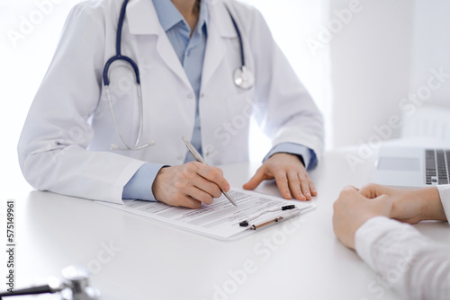 Doctor and patient discussing current health questions while sitting opposite of each other at the table in clinic  just hands closeup. Medicine concept