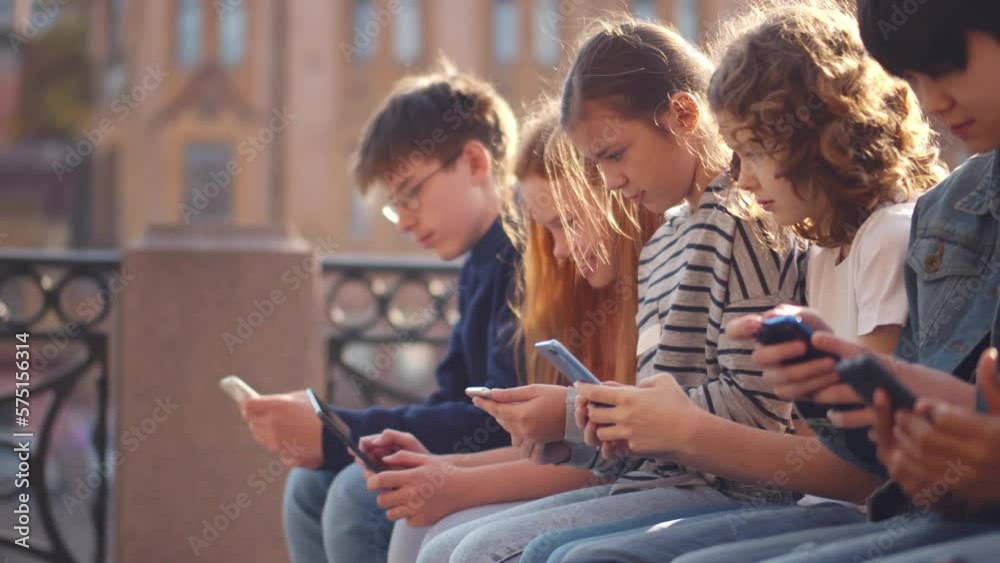Multiethnic group of school students outdoors use mobile phones. Realtime