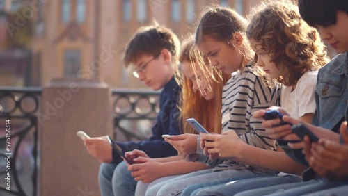 Multiethnic group of school students outdoors use mobile phones. Realtime