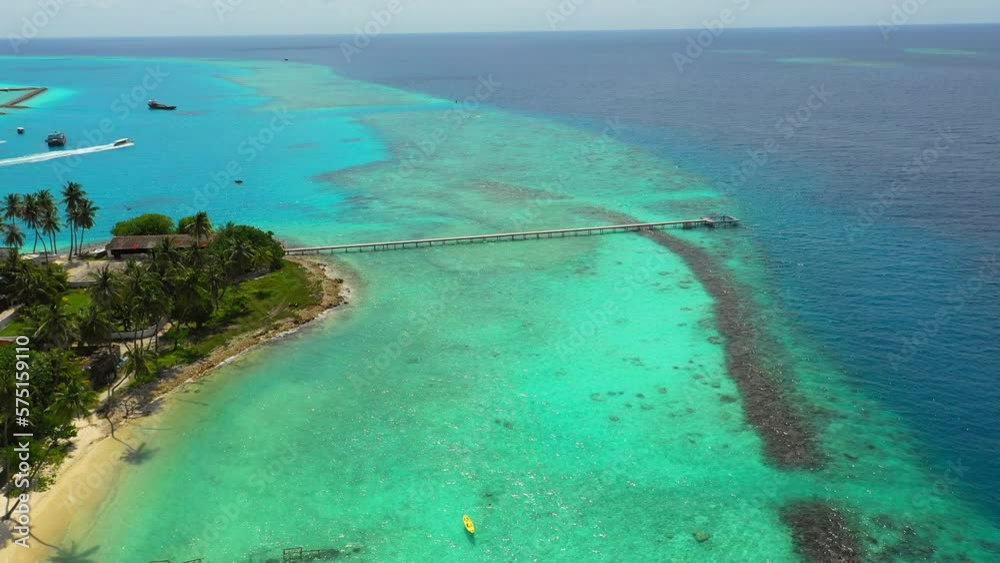 Aerial Beautiful View Of Pier Extending From Island, Drone Flying Forward Over Turquoise Sea On Sunny Day - Thulusdhoo, Maldives