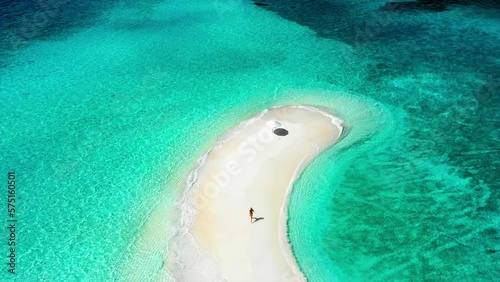 Aerial Ascending Tilt Down Shot Of Happy Female Tourist Running On Beach Amidst Turquoise Sea Against Cloudy Sky During Sunny Day - Thulusdhoo, Maldives photo