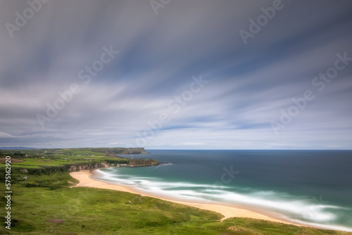 Whitepark Bay Beach and Portbradden Harbour with cliffs, sandy beach, blurred water and sky on long exposure. Causeway Coast, Antrim, Northern Ireland photo