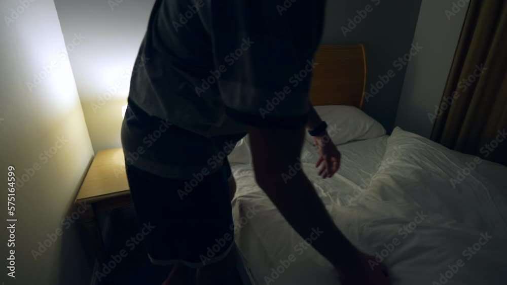 Man prepares to go to bed and sleep. Person lays down in bed and turns off night stand besides bed Man prepares to go to bed and sleep. Person lays down in bed and turns off night stand besides bed