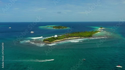 Aerial Shot Of Nautical Vessels Moving Around Island, Drone Ascending Backwards Over Sea On Sunny Day - Thulusdhoo, Maldives photo