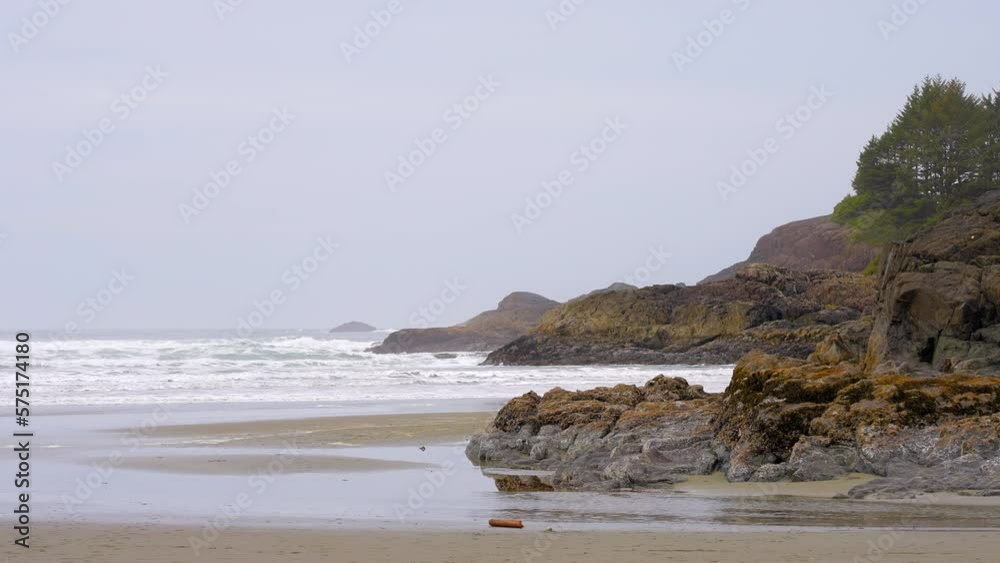 Establishing shot of ocean beach with waves, rocks and sand in slow motion at summer day in Vancouver, Canada, North America. Day time on February 2023. Still camera. ProRes 422 HQ. Establishing shot of ocean beach with waves, rocks and sand in slow motion at summer day in Vancouver, Canada, North America. Day time on February 2023. Still camera. ProRes 422 HQ.