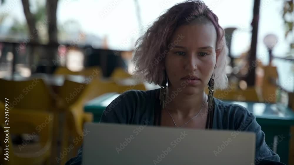 A young lady sits at a computer in a cafe and diligently does her job. A young lady sits at a computer in a cafe and diligently does her job.
