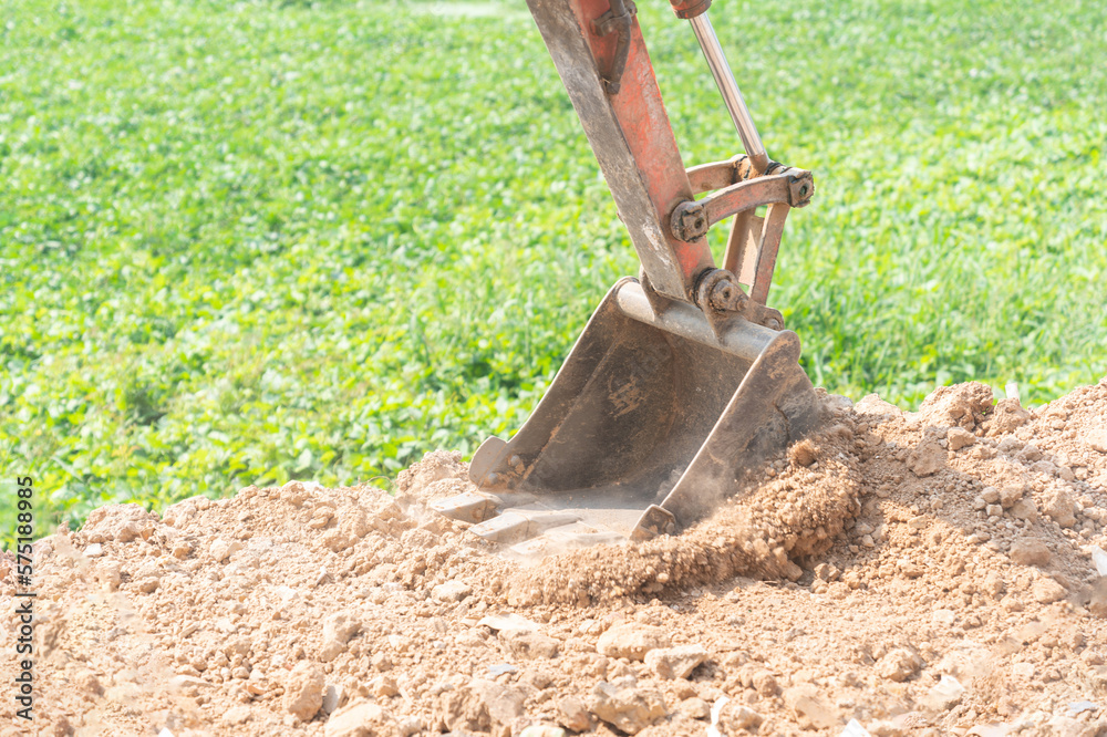 Fototapeta premium Close up of mini digger bucket excavating the ground.