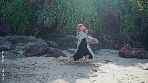 A young beautiful girl in a dress with pink hair dances a crazy dance