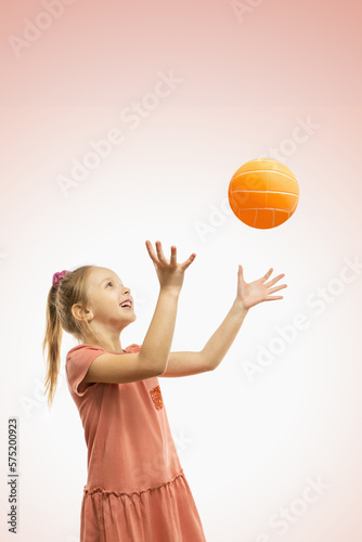 A cute happy girl throwing a ball.