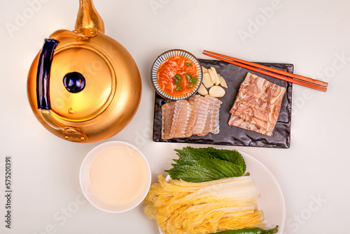 Table setting with makgeolli, pork sliced meat, and skate ray sashimi