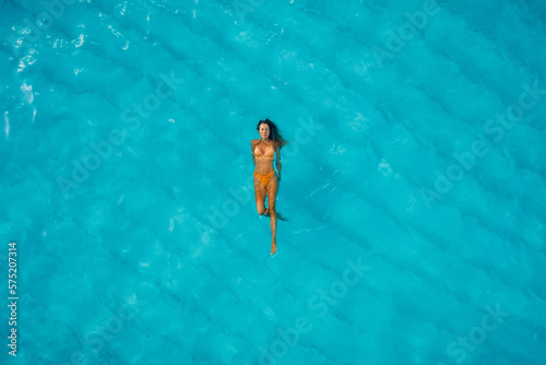 Slim woman swimming in blue ocean. Aerial view, top view.