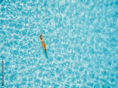 Beautiful woman floating in blue ocean. Aerial view, top view