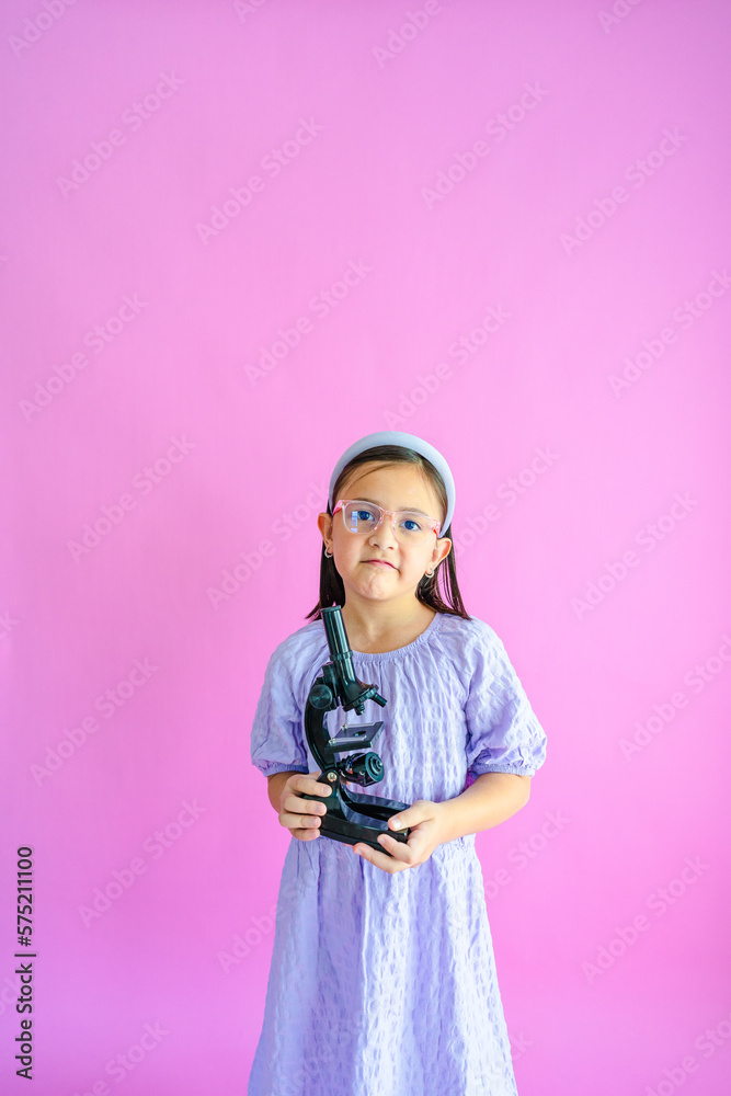 Pretty little girl holding a compound microscope in her hands. Pretty little girl holding a compound microscope in her hands.