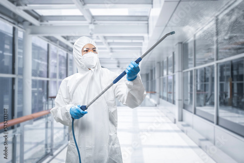 Tablou pe pânză Worker wears medical protective suit or coverall suit sanitize with spray