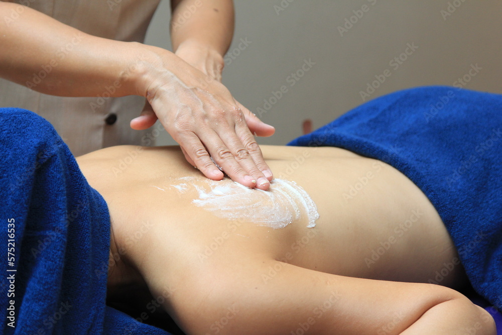 Fototapeta premium Young woman undergoing treatment with body scrub in spa salon