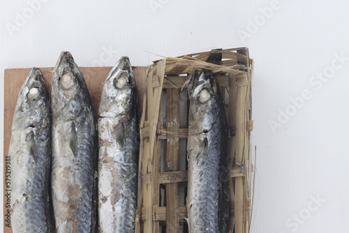 Pindang fish (salted fish) in a bamboo container and on a wooden cutting board, is one of the traditional Indonesian fish processing methods.isolated on a white background. photo