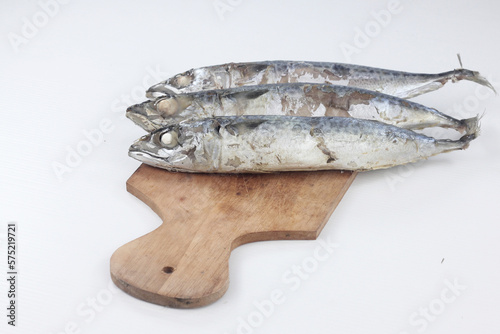 Pindang fish (salted fish) on a wooden chopping board, is one of the traditional Indonesian fish processing methods, isolated on a white background. photo