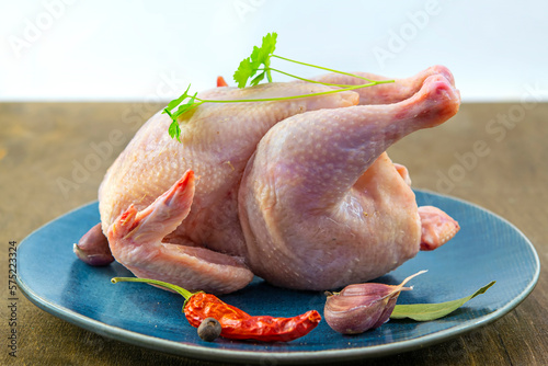 Carcass of raw chicken of the gherkin breed on a blue plate, raw chicken meat