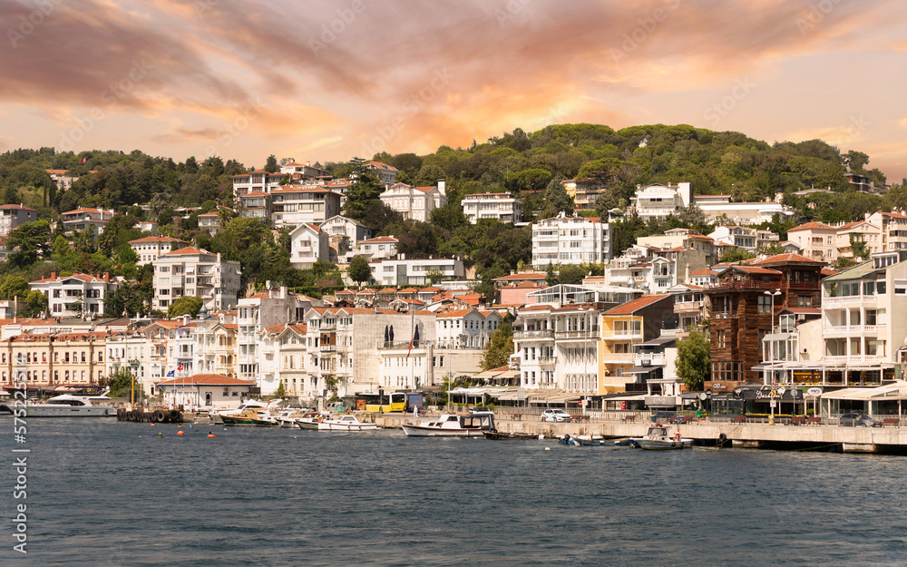 View from the sea of the green mountains of the Europian side of Bosphorus strait, with docked boats, traditional houses and dense trees in a summer day, Arnavutkoy district, Istanbul, Turkey