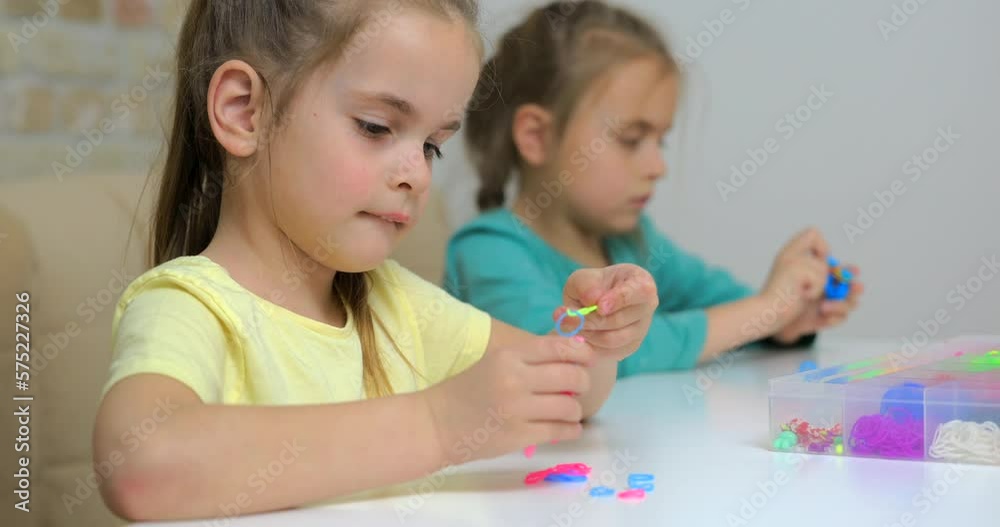 Girl weaving bracelets made of multicolored rubber bands Girl weaving bracelets made of multicolored rubber bands
